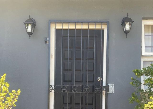 Two outdoor wall lanterns either side of a security-gated front door