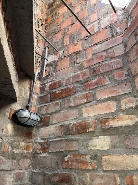 Outdoor bulkhead light fitting on a brick wall with its conduit run